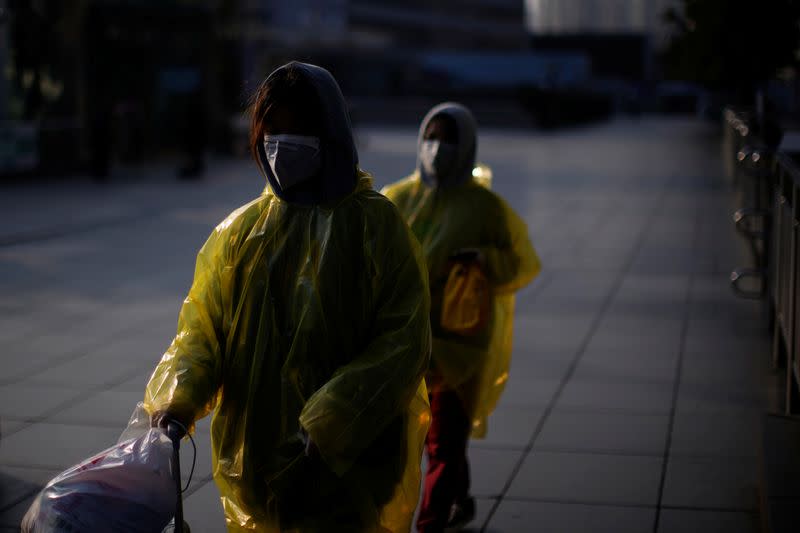 Women wearing masks and plastics rain coat as protection from a coronavirus are seen at the Shanghai railway station in Shanghai