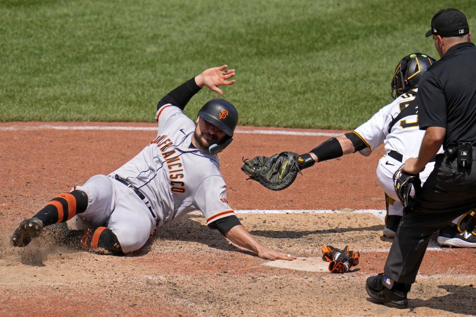 San Francisco Giants' J.D. Davis, left, scores around a tag-attempt by Pittsburgh Pirates catcher Jason Delay, second from right, the second of two runs driven in on a double by Michael Conforto off Pirates relief pitcher Yerry De Los Santos during the 10th inning of a baseball game in Pittsburgh, Sunday, July 16, 2023. (AP Photo/Gene J. Puskar)