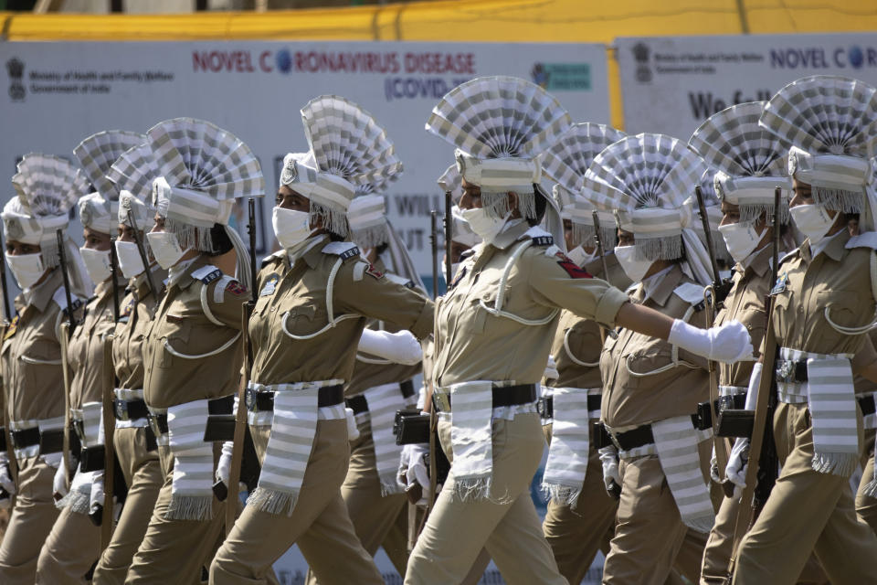 Jammu Kashmir police women wearing face masks as a precaution against the coronavirus march past a signage about the precautions to be taken against COVID-19 during full dress rehearsals of India's Independence Day ceremony in Srinagar, Indian controlled Kashmir, Thursday, Aug. 13, 2020. India celebrates Independence Day on Aug.15. (AP Photo/Mukhtar Khan)