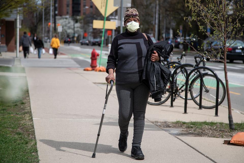 Tina Harris, of Ann Arbor, with her mask on, walks down East William Street toward the bus stop in Ann Arbor on April 19, 2023.