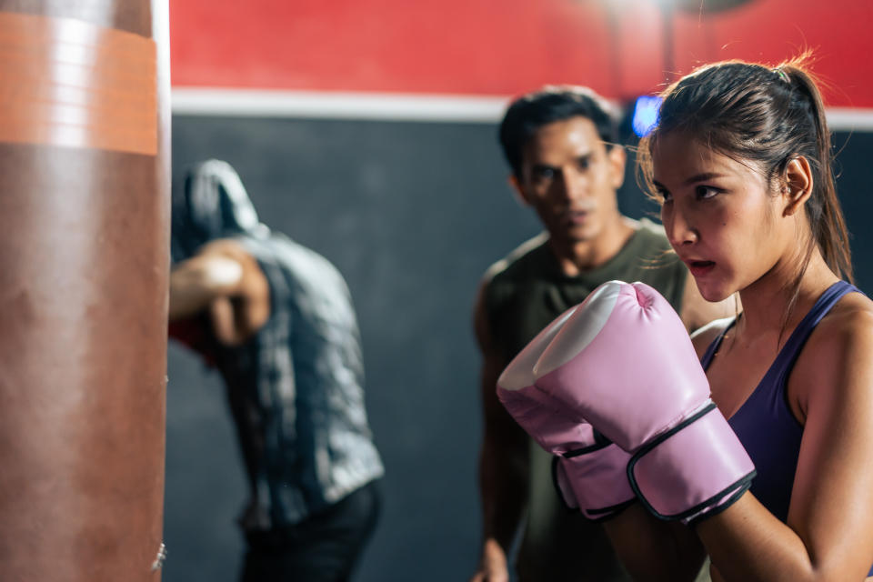 A woman learning Muay Thai in a gym. 