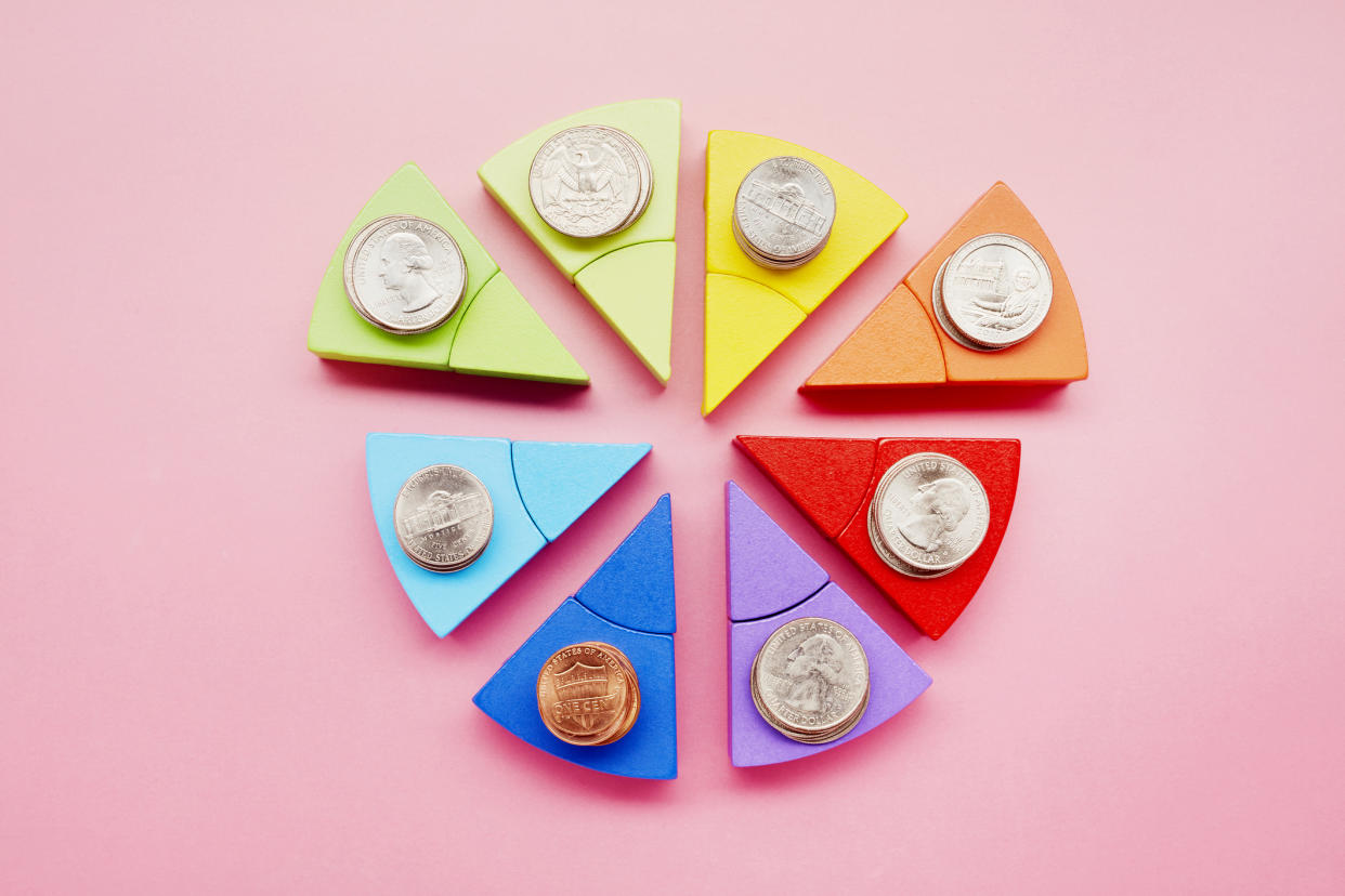  Pie chart made of colorful building blocks and stacks of American Dollar coins on pink background . 