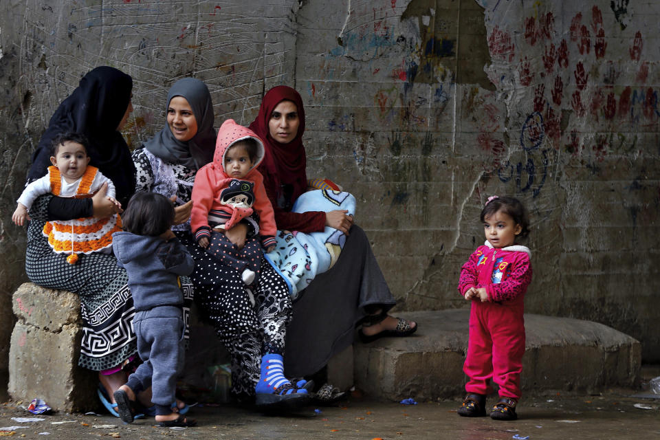 In this Tuesday, Dec. 18, 2018, photo, Syrian refugees women hold their children as they sit in Ouzai refugee compound, in the southern port city of Sidon, Lebanon. A much touted Russian initiative to facilitate the return of Syrian refugees has fizzled out, with the return of only about 114,000 Syrians - out of more than 5 million in the region and Europe. In Lebanon, which hosts the highest ratio of refugees per capita, most of the estimated 1.2 million Syrians say the intend to stay put, citing economic concerns, ongoing fighting and destroyed homes. (AP Photo/Bilal Hussein)