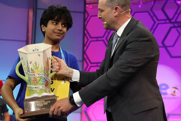 NATIONAL HARBOR, MARYLAND - JUNE 01:  Speller Dev Shah of Largo, Florida, is presented with a trophy by E. W. Scripps Company CEO Adam Symson after he won the 2023 Scripps National Spelling Bee at Gaylord National Hotel and Convention Center on June 1, 2023 in National Harbor, Maryland. Shah correctly spelled the word 