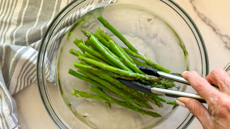 hand with tongs on asparagus