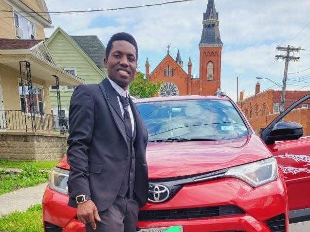 Abdul Sharifu stands in front of a red car.