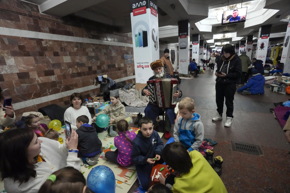 An elderly man plays the accordion to amuse children in a city subway that people have used as a bomb shelter for over three weeks in Kharkiv, Ukraine, Thursday, March 24, 2022. Kharkiv is Ukraine's second biggest city 30 kilometers of the Russian border. (AP Photo/Efrem Lukatsky)