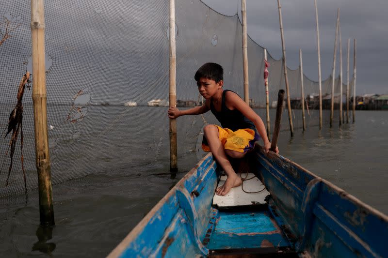 The Wider Image: Rising seas threaten early end for sinking village in Philippines