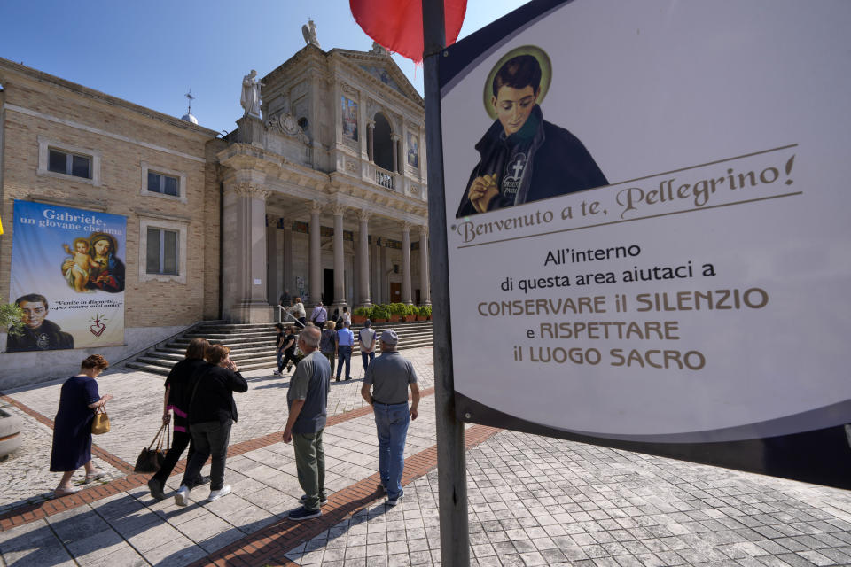 People arrive at St. Gabriele dell'Addolorata sanctuary in Isola del Gran Sasso near Teramo in central Italy Sunday, June 18, 2023. Placard in Italian reads: "Welcome to you, pilgrim! Inside this area please help us to preserve silence and respect the holy place". (AP Photo/Domenico Stinellis)