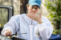 Beekeeper Erin Gleeson licks honey from a knife after helping to remove a swarm of honeybees from a fence line in a neighborhood in Anacostia, Monday, April 20, 2020, in Washington. (AP Photo/Andrew Harnik)