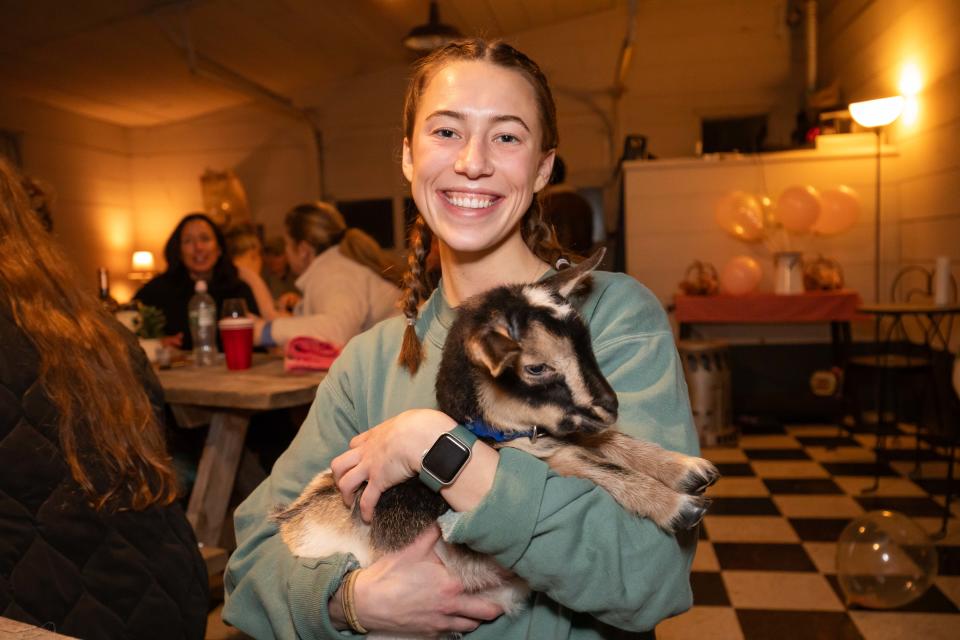 Mel Drexler of Rockport, Massachusetts, holds one of the baby goats at Wine-yasa Goat Yoga night at Legacy Lane Farm in Stratham.