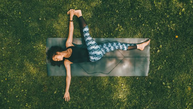 woman doing yoga stretch on park grass