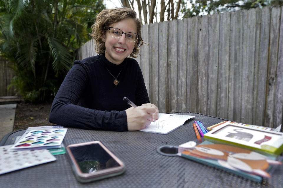 Kara McKlemurry poses for a photo while writing Thanksgiving notes to family and friends at her home Thursday, Nov. 19, 2020, in Clearwater, Fla. On any normal Thanksgiving Day, McKlemurry and her husband would drive from their home to one of two places: his family's home in another part of Florida or her family's house in Alabama. This year, McKlemurry informed her family there would be no visits because of the pandemic. (AP Photo/Chris O'Meara)