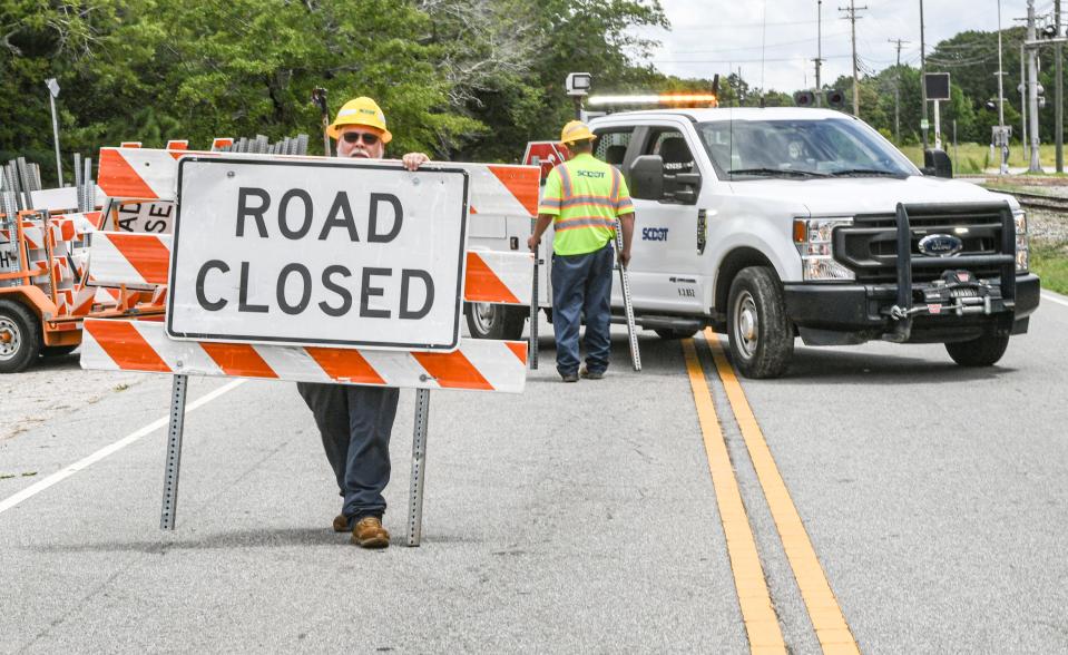 SCDOT workers place road closed signs on the perimeter of the scene where a train derailment happened earlier in the day along State Highway 20, just outside the city limits of Belton, S.C. Thursday, July 25, 2024.