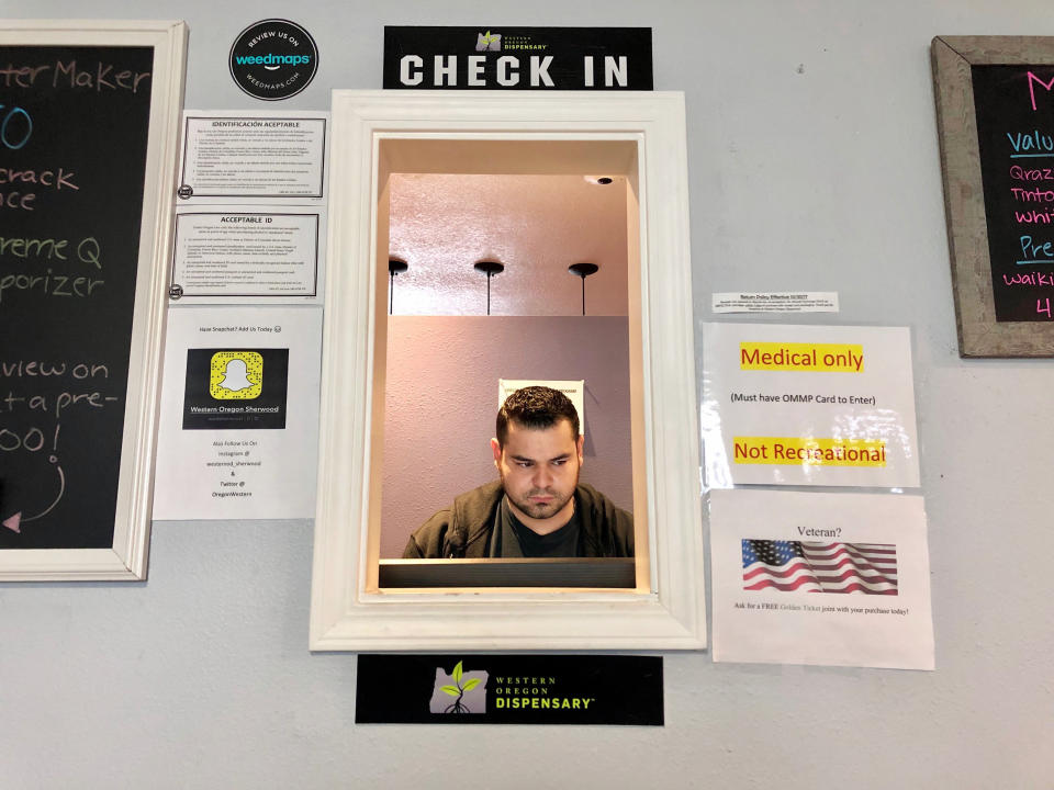 In this April 8, 2019, photo, Roberto Gonzalez, the general manager of Western Oregon Dispensary in Sherwood, Ore., waits for customers. The dispensary is one of two medical-only marijuana dispensaries left in Oregon. An Associated Press analysis has found existing medical marijuana programs take a hit when states legalize cannabis for all adults. (AP Photo/Gillian Flaccus)