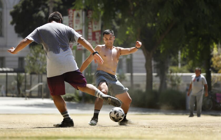 LOS ANGELES, CA - SEPTEMBER 1, 2022: David Orantes, left, and Julio Ruiz play soccer in the hot sun at Grand Park in downtown Los Angeles on Thursday, September 1, 2022. (Christina House / Los Angeles Times)