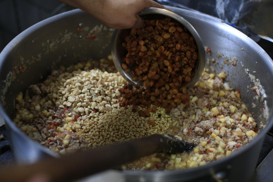 ARCHIVO - El jefe de cocina, Erick Pérez, agrega pasas, almendras, piñones y múltiples tipos de frutas a la carne molida mientras prepara el relleno para chiles en nogada, en la cocina del restaurante Arango, en la Ciudad de México, el 6 de septiembre de 2019. (AP Foto/Rebecca Blackwell, Archivo)