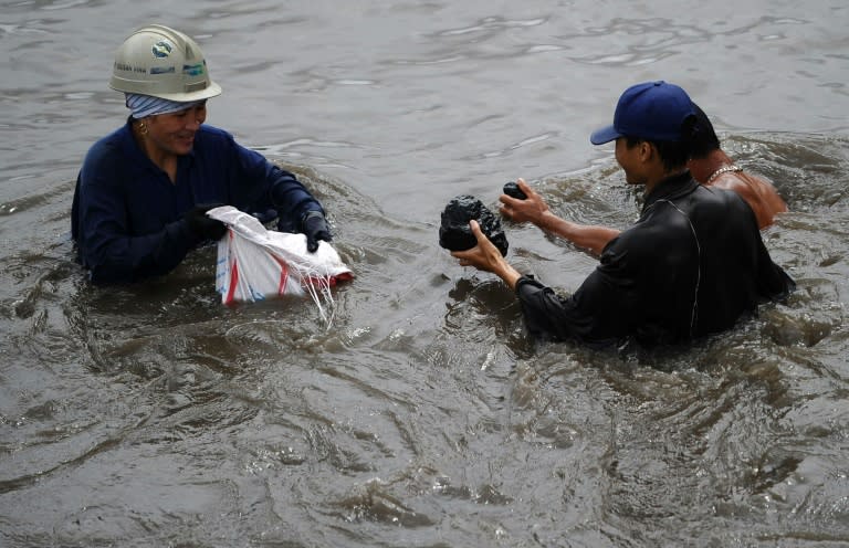 People collecting coal from a flooded river next to the Mong Duong coal mine on August 1, 2015 following heavy rains in the northern coastal province of Quang Ninh