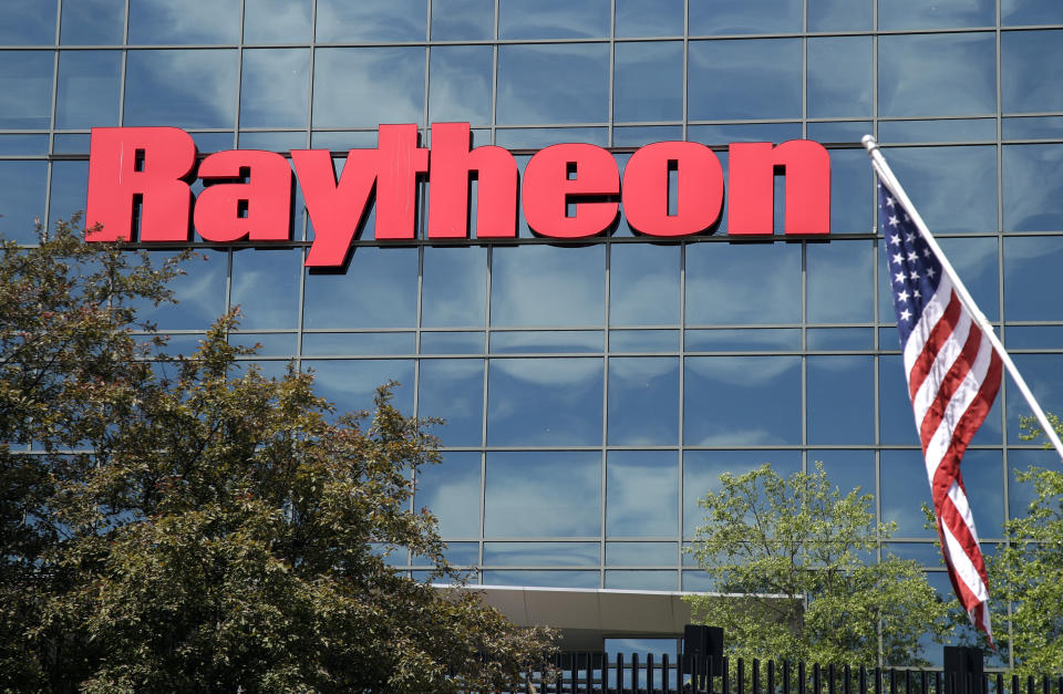 FILE - In this June 10, 2019, file photo, an American flag flies in front of the facade of Raytheon's Integrated Defense Systems facility, in Woburn, Mass. China's government said Monday, Oct. 26, 2020, it will impose sanctions on U.S. military contractors including Boeing Co.'s defense unit and Lockheed Martin Corp. for supplying weapons to rival Taiwan, stepping up a feud with Washington over security and Beijing's strategic ambitions. (AP Photo/Elise Amendola, File)