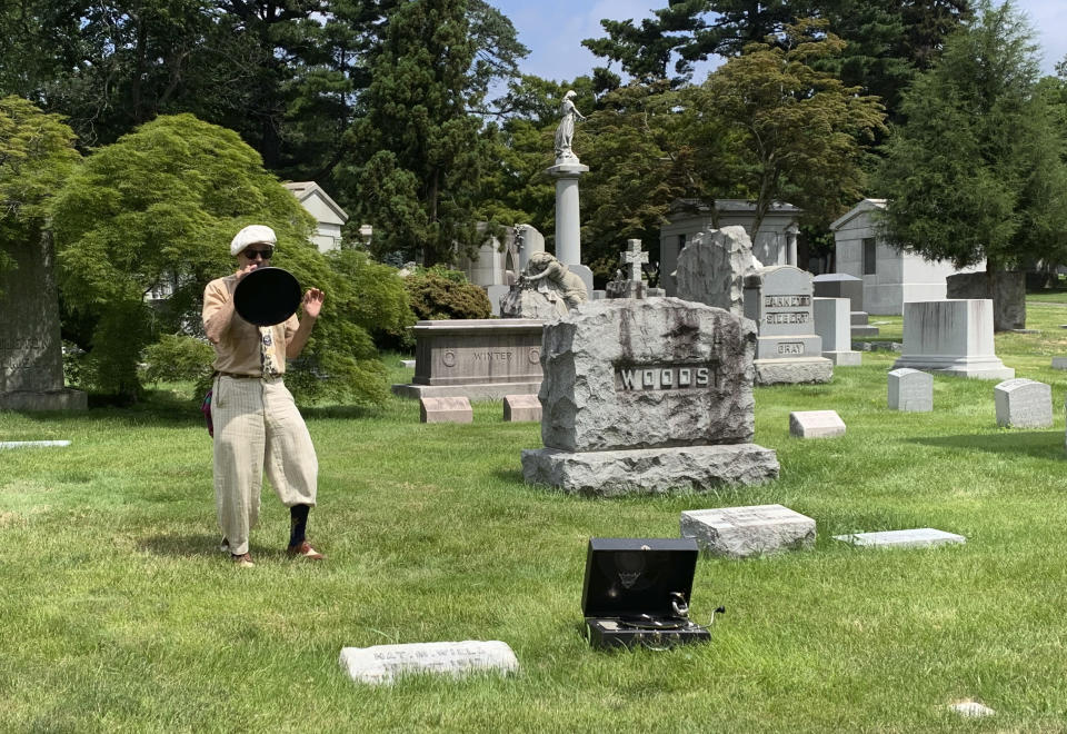 Michael Cumella, aka DJ MAC, speaks through a vintage megaphone near the gravesite of Nat M. Wills, a vaudeville star of the early 20th century known as “The Happy Tramp" at Woodlawn Cemetery in the Bronx on June 27, 2021. Wills was among the jazz and vaudeville greats included on a tour led by Cumella. (AP Photo/Julia Rubin)