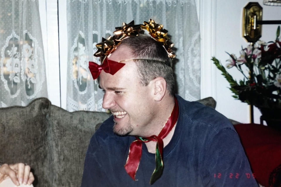 In this Dec. 2005 photo provided by Kathleen McIlvain of Charles McIlvain, he laughs while wearing a "bow hawk" made of gift wrap bows on his head at a Christmas family gathering. Charles McIlvain was one of 34 people killed when the dive boat Conception caught fire and sank off the coast of California on Sept. 2, 2019. (Kathleen McIlvain via AP)