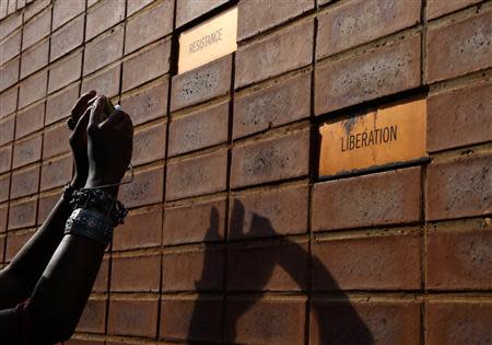 A mourner takes photos of a brick wall in the house of Nelson Mandela in Soweto in the outskirts of Johannesburg December 7, 2013. REUTERS/Yannis Behrakis