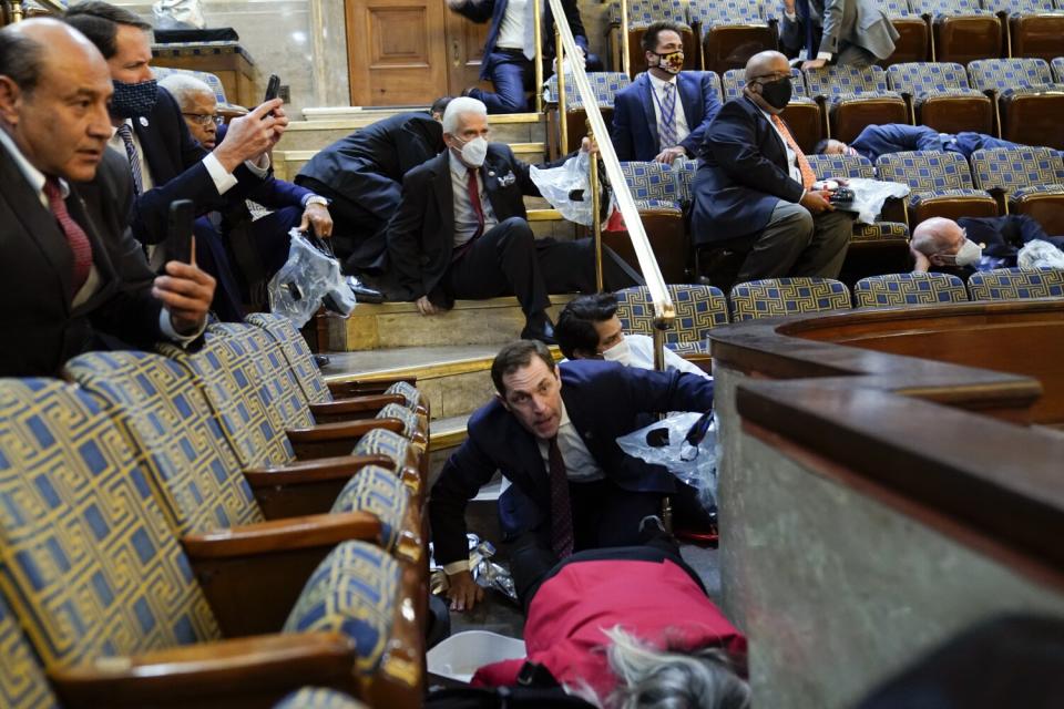 Several people crouching down in the House gallery as a few point their smartphones at the action below