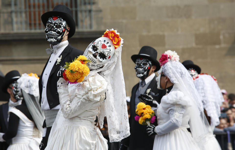 Performers in costume attend a Day of the Dead parade in Mexico City, Sunday, Oct. 27, 2019. The parade on Sunday marks the fourth consecutive year that the city has borrowed props from the opening scene of the James Bond film, "Spectre," in which Daniel Craig's title character dons a skull mask as he makes his way through a crowd of revelers. (AP Photo/Ginnette Riquelme)