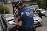 Local police stop vehicles at a checkpoint in Madrid, Spain, Wednesday, Sept. 23, 2020. Madrid is poised to extend its restrictions on movement to more neighborhoods, due to a surge in new cases in other districts and despite an outcry from residents over discrimination. Police on Monday deployed to 37 working-class neighborhoods that have seen 14-day transmission rates above 1,000 per 100,000 inhabitants. (AP Photo/Bernat Armangue)