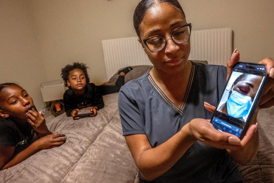 Nia Love holds her cellphone on Oct. 24, 2023, showing a photograph of her injured left eye in 2020 after she was blinded by a rubber bullet shot by police while she was attending a George Floyd protest in Sacramento. Her daughters Lyric, 11, and Adaya, 9, watch behind her. “There needs to be some accountability on the police's end,” she said. “I would even accept an apology.”