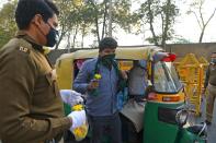 A policeman gives a flower to an auto rickshaw driver in a bid to inspire him to stay home during a one-day Janata (civil) curfew imposed as a preventive measure against the COVID-19 coronavirus, in New Delhi on March 22, 2020. - Nearly one billion people around the world were confined to their homes, as the coronavirus death toll crossed 13,000 and factories were shut in worst-hit Italy after another single-day fatalities record. (Photo by Sajjad HUSSAIN / AFP) (Photo by SAJJAD HUSSAIN/AFP via Getty Images)