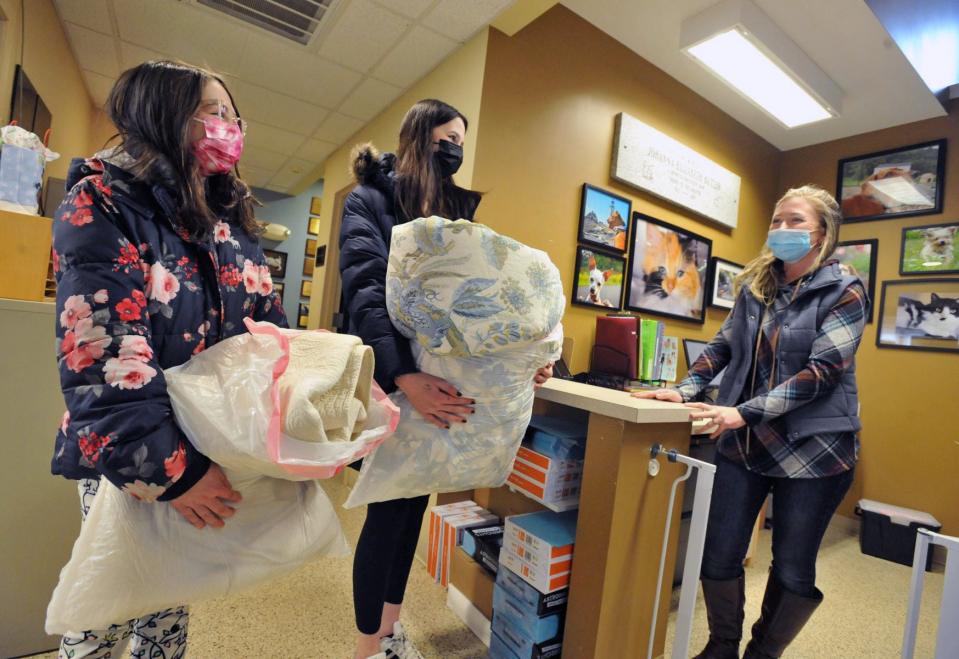 Scituate Animal Shelter operations assistant Lindsay Kimball, right, greets Lilly Sullivan of Scituate, 10, left, and her sister, Anja Sullivan, 13, center, as they bring a donation of bedding to the shelter during the Betty White Challenge, in which donations were made to local animal shelters in honor of the late actress Monday, Jan. 17, 2022.