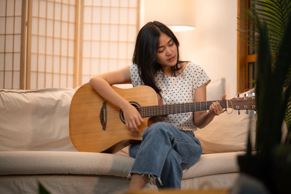 woman playing guitar on the sofa