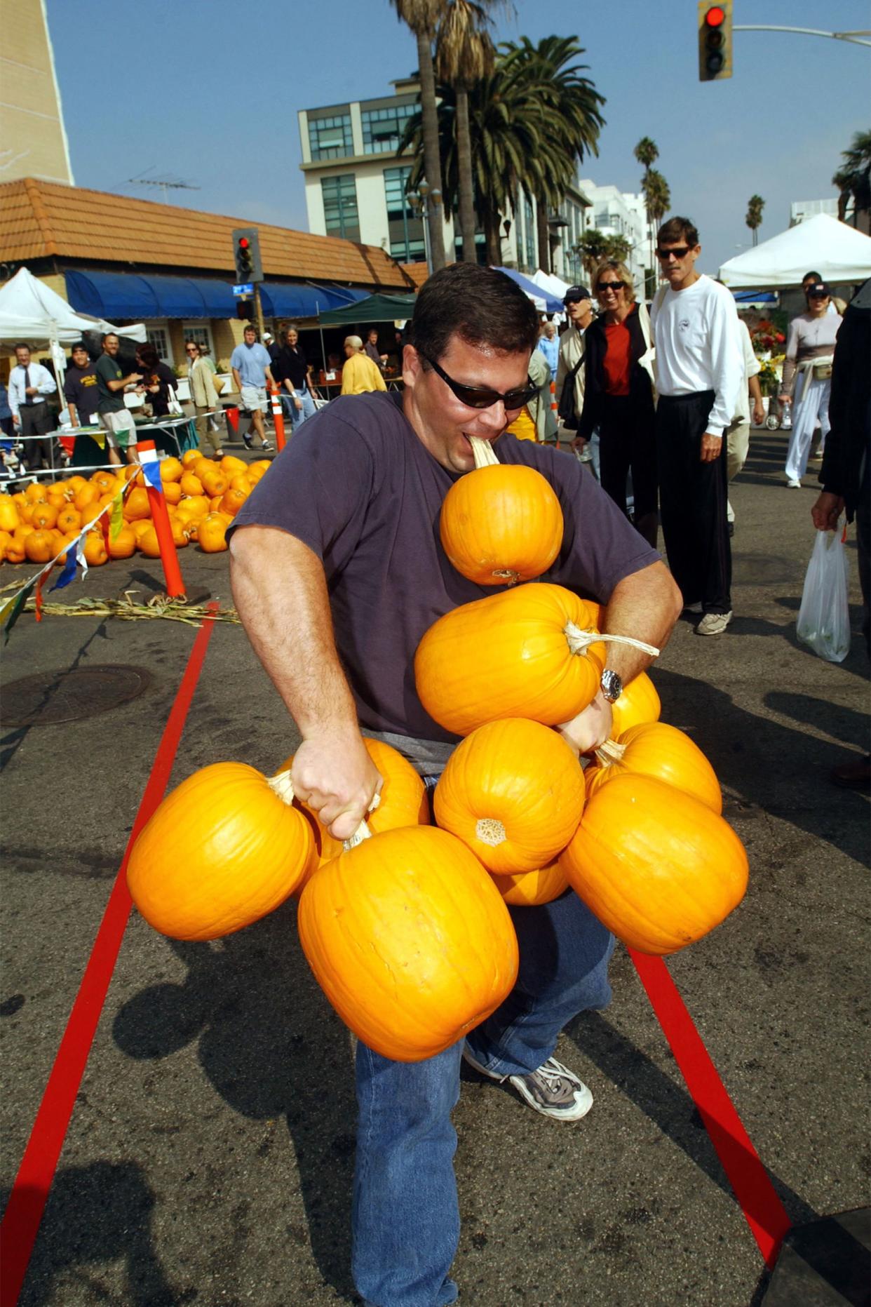 For $5, Mike Santini carries all the pumpkins he can carry, which in his case was 10, down a 25-foot walkway during a promotion at a farmer's market October 30, 2002 in Santa Monica, California.