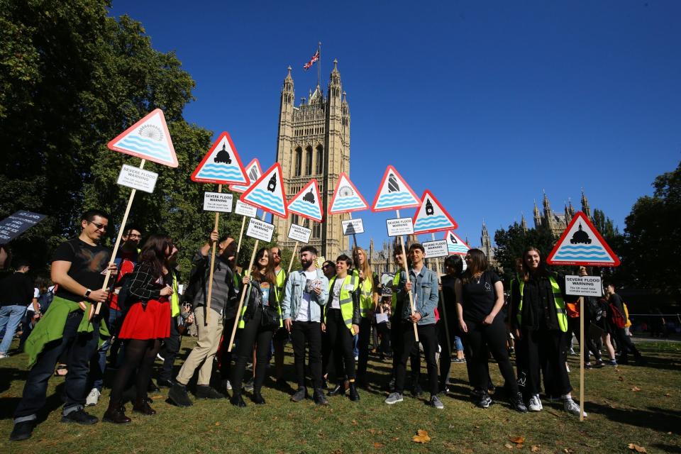 Protesters hold flood warning signs at the UK Student Climate Network's Global Climate Strike at Millbank. (PA)