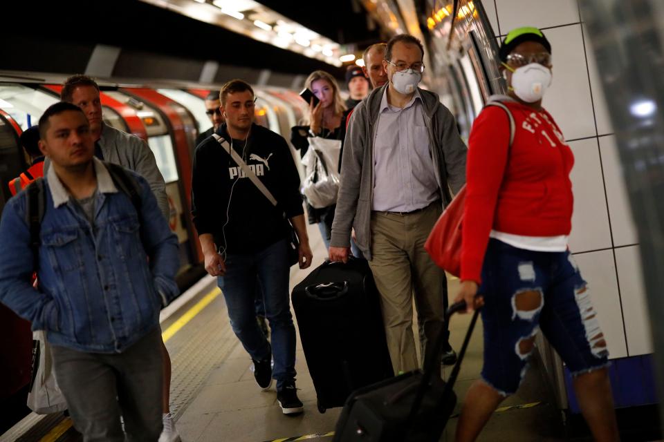 Commuters, wearing PPE (personal protective equipment) as a precautionary measure against COVID-19, walk along the platform at a tube station in London on April 22, 2020, as Britain remains under lockdown during the novel coronavirus COVID-19 pandemic. - British Prime Minister Boris Johnson tentatively began his return to work on Tuesday after being hospitalised for coronavirus, as parliament returned and criticism grew over the government's response to the outbreak. (Photo by Tolga Akmen / AFP) (Photo by TOLGA AKMEN/AFP via Getty Images)