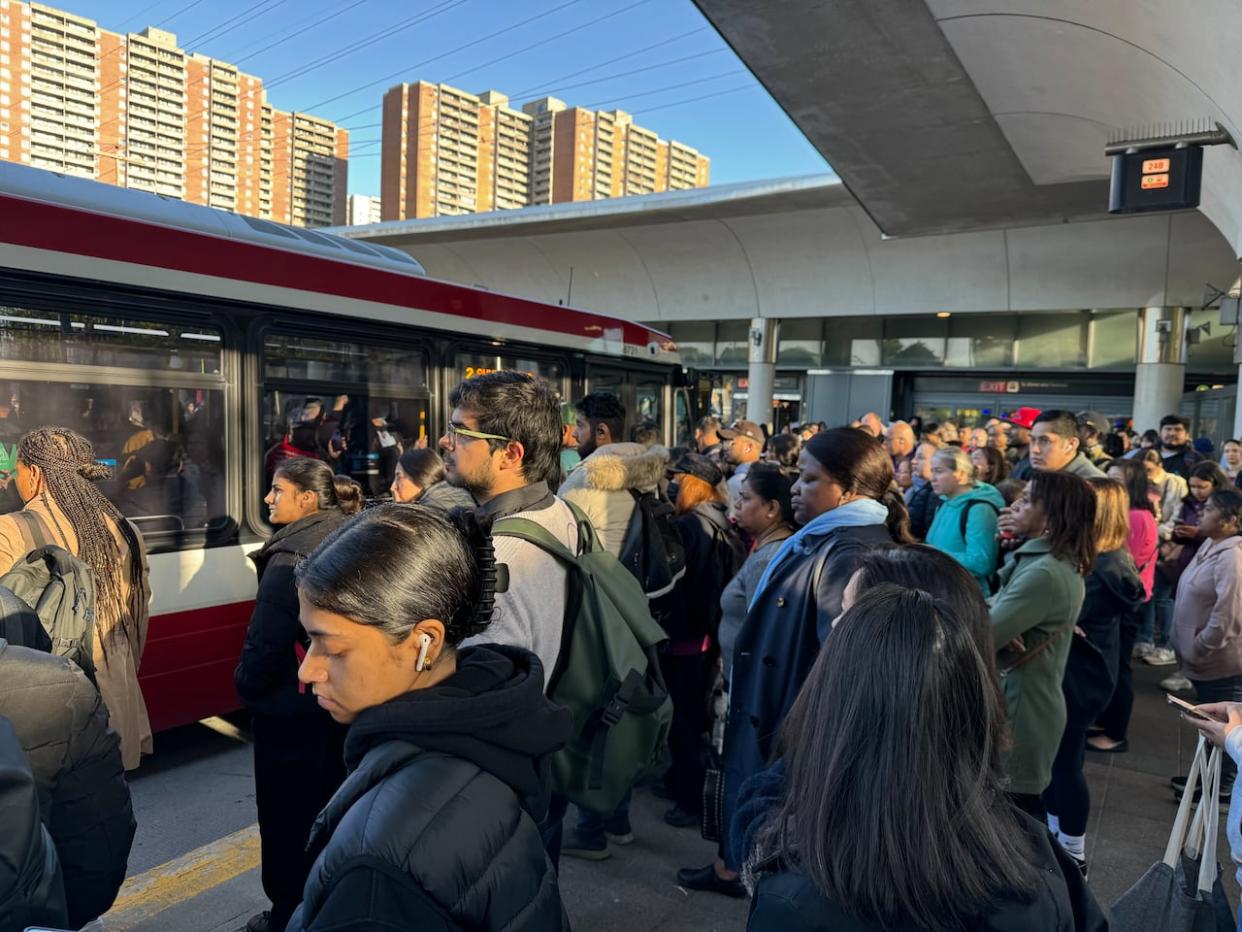 Commuters line up for buses at Victoria Park subway station on Thursday morning, where Line 2 trains had been turning back due to a technical issue. Subway service is now back up and running, the TTC said. (Aaron Saltzman/CBC - image credit)