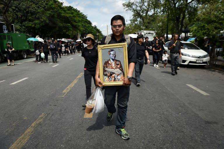 A mourner clad in black carries a painting of the late Thai King Bhumibol Adulyadej to the Grand Palace in Bangkok on October 22, 2016