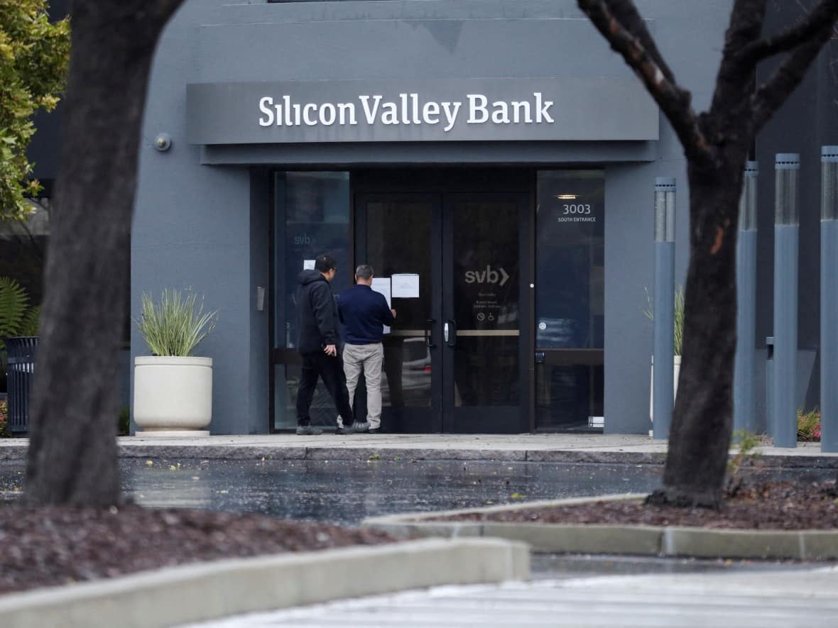 A man puts a sign on the door of the Silicon Valley Bank at the bank’s headquarters in Santa Clara, Calif. on Friday. (Nathan Frandino/Reuters - image credit)