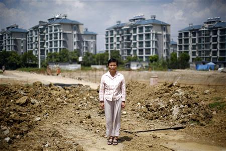 Xu Haifeng poses at a construction site area where her house stood in Wuxi, Jiangsu province, August 20, 2013. REUTERS/Carlos Baria