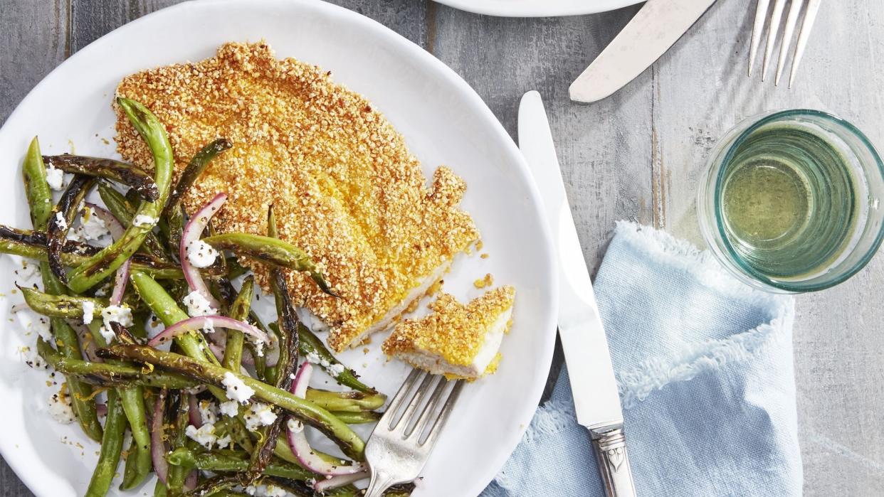 spiced grit fried chicken cutlets on white plates with red onion and feta green beans on the side