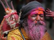 A Sadhu, or Hindu holy man reacts after a boy, only hands seen, rubs colored powder on his face during "Holi" celebrations at Kamakhya temple in Gauhati, India, Saturday, March 3, 2007. Holi, the Hindu festival of colors, also heralds the coming of spring. (AP Photo/Anupam Nath)