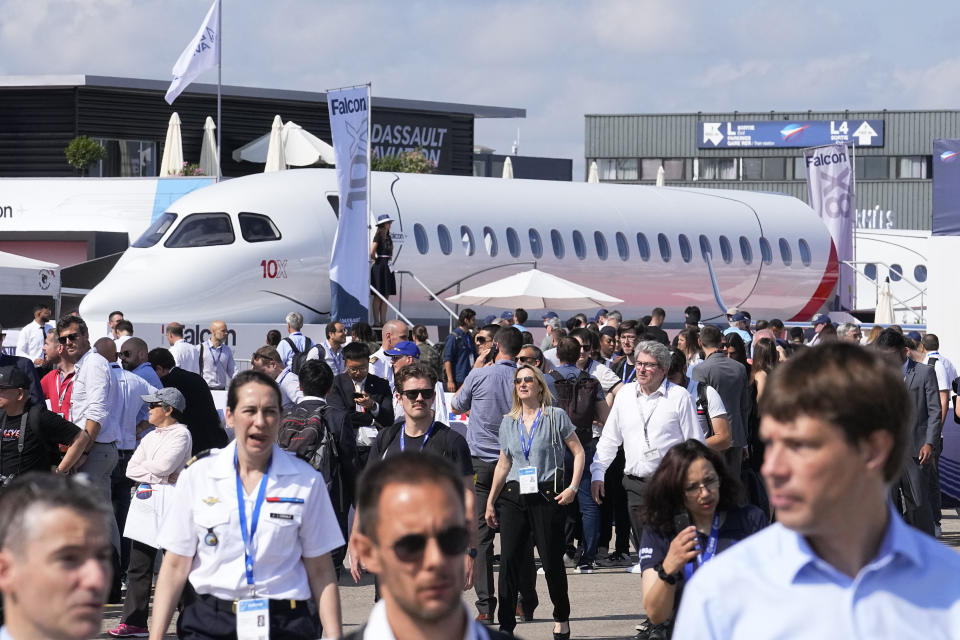 FILE - Visitors walk by a Falcon 10X prototype by the French manufacturer Dassault Aviation, at the Paris Air Show, Wednesday, June 21, 2023 in Le Bourget, north of Paris. Airlines are facing increasing pressure to cut their climate-changing emissions. That made sustainable aviation fuel a hot topic this week at the Paris Air Show, a major industry event. Sustainable fuel made from food waste or plant material is aviation's best hope for reducing emissions in the next couple of decades. (AP Photo/Michel Euler, File)