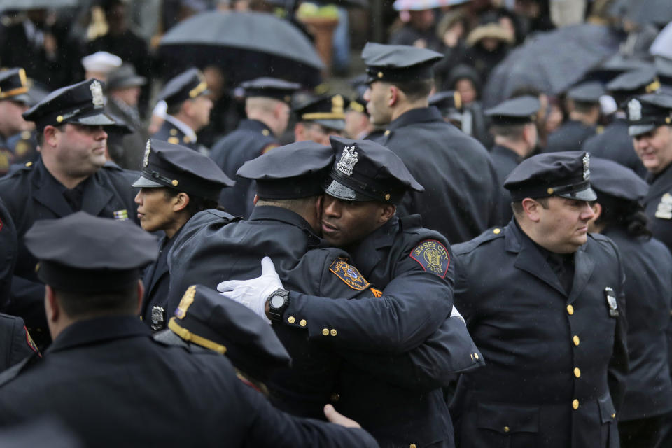 Jersey City police officers comfort one another after the funeral for Jersey City Police Detective Joseph Seals in Jersey City, N.J., Tuesday, Dec. 17, 2019. The 40-year-old married father of five was killed in a confrontation a week ago with two attackers who then drove to a kosher market and killed three people inside before dying in a lengthy shootout with police. (AP Photo/Seth Wenig)