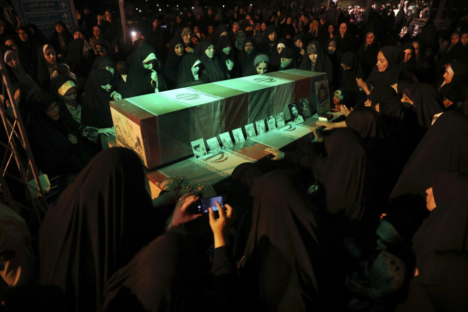 Women mourn over the flag-draped coffins of soldiers who were killed during the 1980-88 Iran-Iraq war, whose remains were recently recovered in the battlefields, during a ceremony prior to funeral for 150 soldiers, mostly unknown, Wednesday, June 26, 2019 in Tehran. (AP Photo/Vahid Salemi)