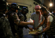 <p>Protesters offer sweets to police officers standing guard during a protest in Amman, Jordan, on June 4, 2018. (Photo: Khalil Mazraawi/AFP/Getty Images) </p>