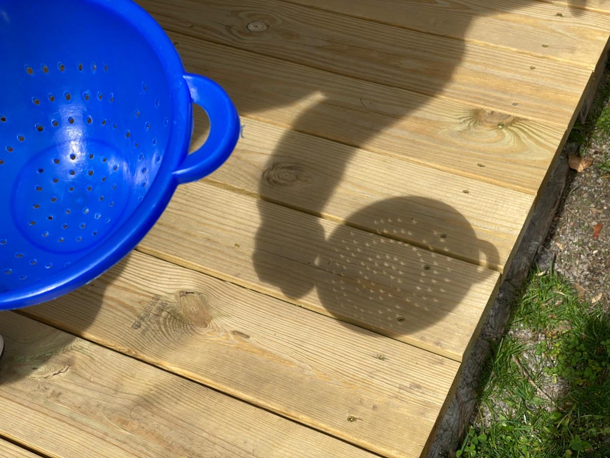 A kitchen colander is used as a pinhole viewer to cast many crescent-shaped images of the moon passing between the Earth and sun during the solar eclipse Monday in Toledo.