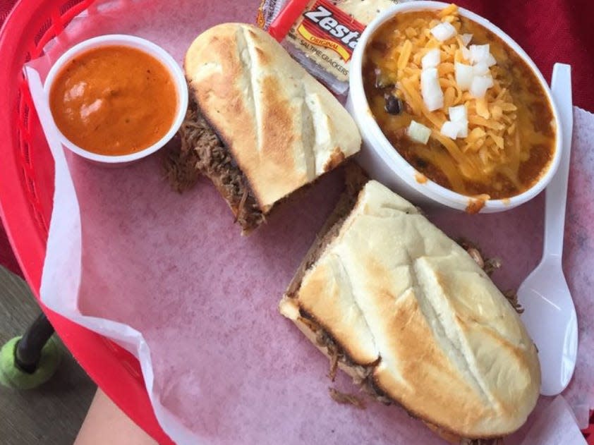 A meat sandwich with sides on a red tray.
