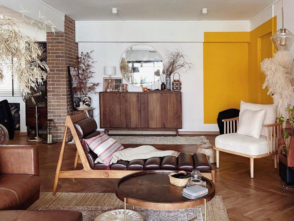 Toh's living room has a bright yellow color block on the wall.