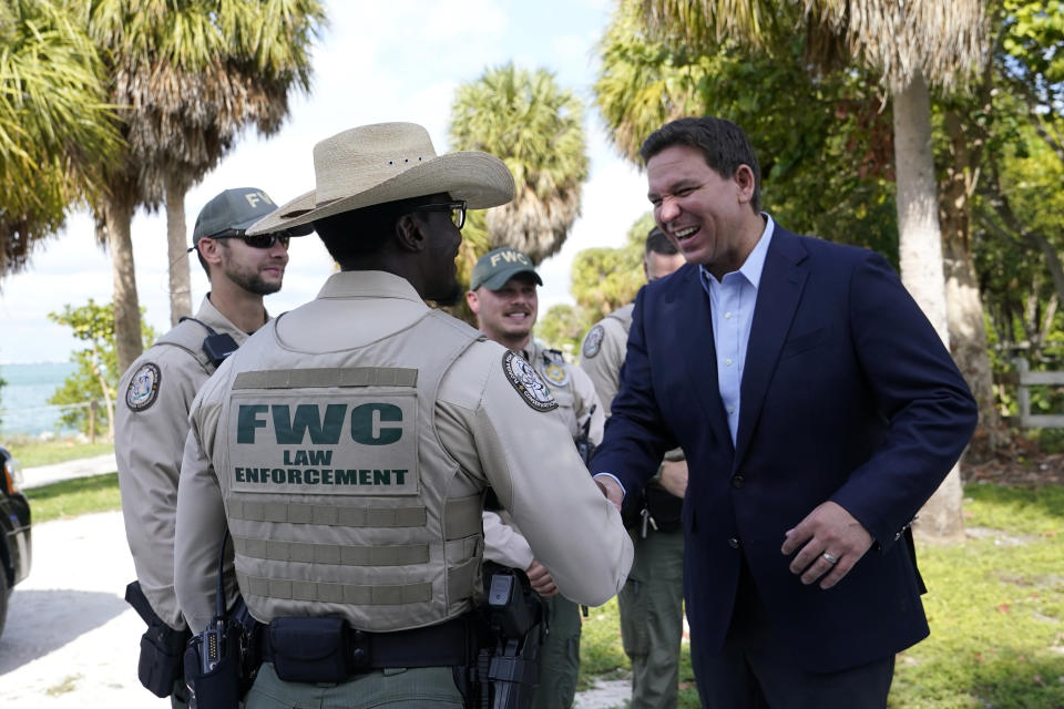 Florida Gov. Ron DeSantis, right, talks with FWC Law Enforcement officers following a news conference at Bill Baggs Cape Florida State Park, Thursday, Dec. 1, 2022, on Key Biscayne, Fla. The Governor announced increased funding for the environmental protection of Biscayne Bay. (AP Photo/Lynne Sladky)